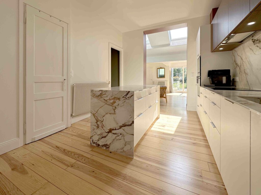 Façade blanche, plan de travail et crédence marbre, table de salle à manger, parquet pin naturel verni