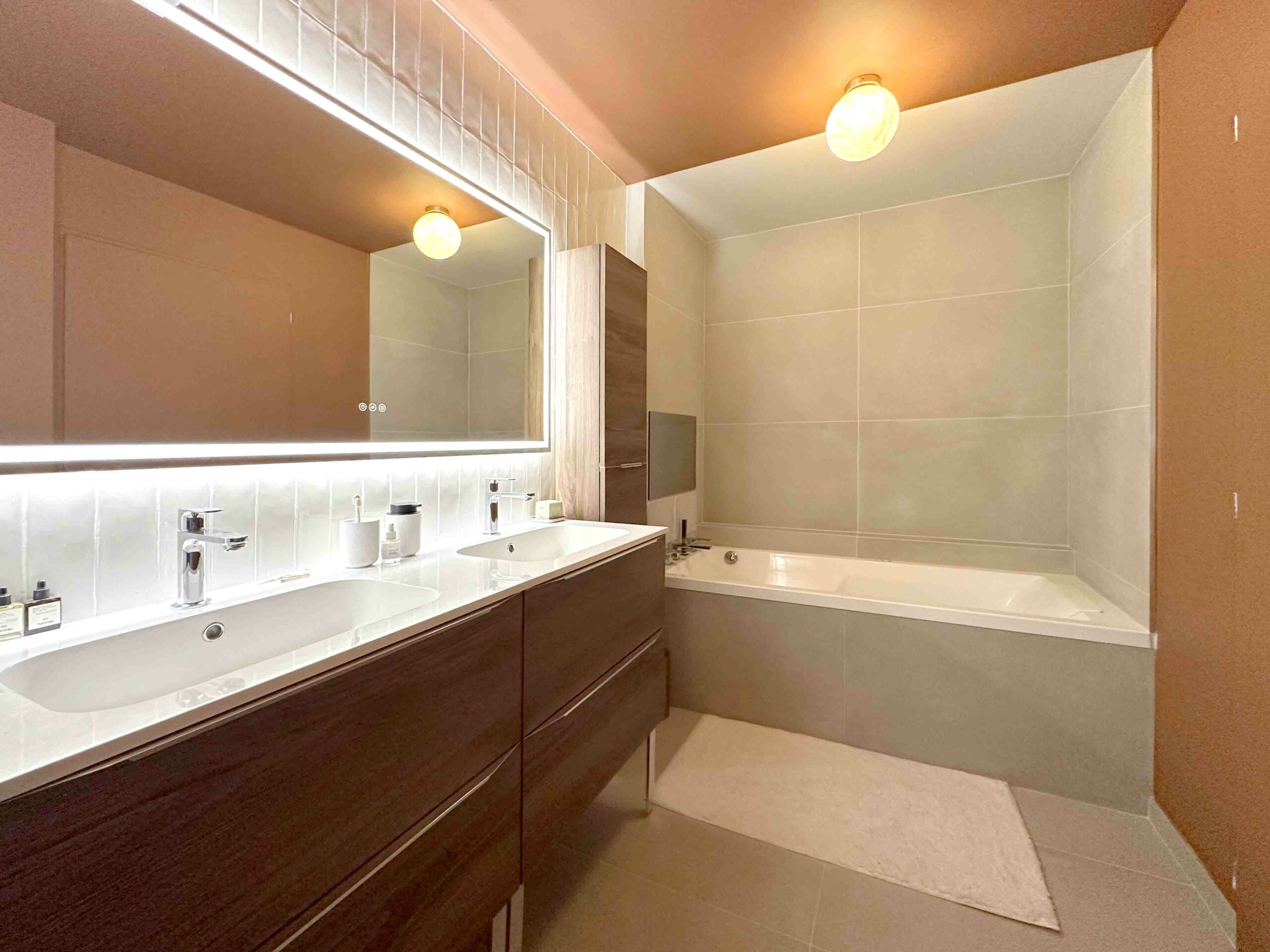Baignoire à remous, peinture terracotta carrelage pierre claire Meuble vasque noyer blanc zellige blanc miroir leds